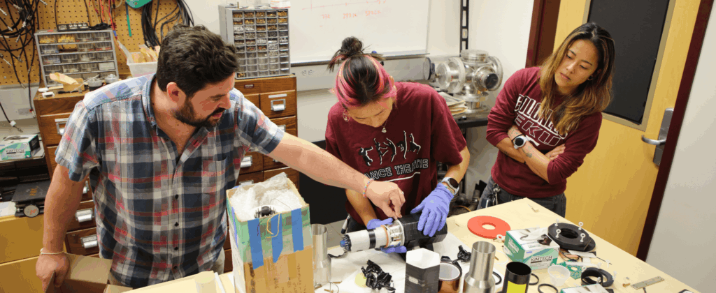 professor works with two students in a physics lab at eku