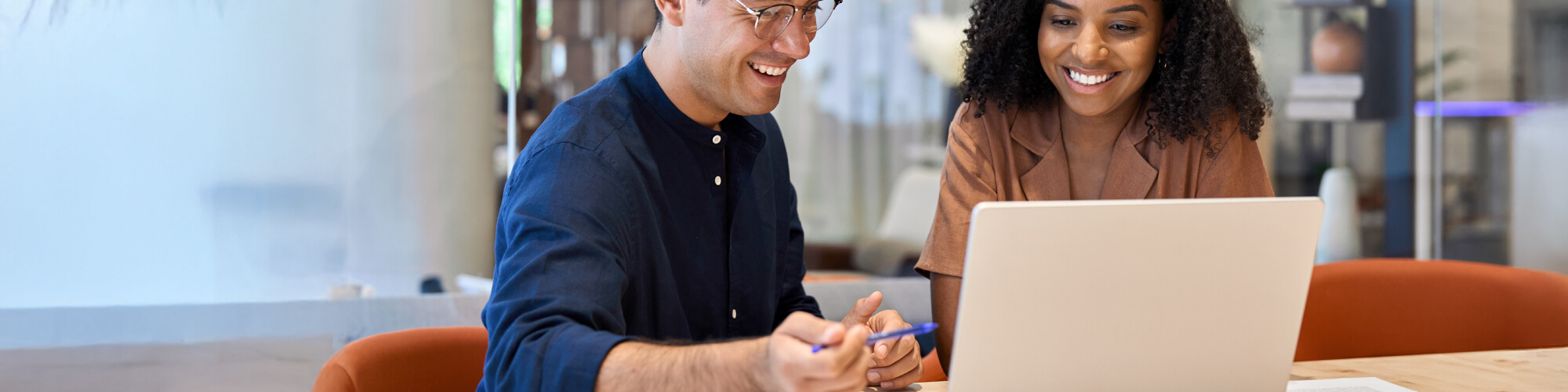 two people work at a laptop smiling