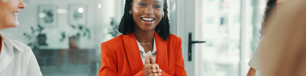 smiling woman centered in the frame with two other people just barely visible on either side of the frame