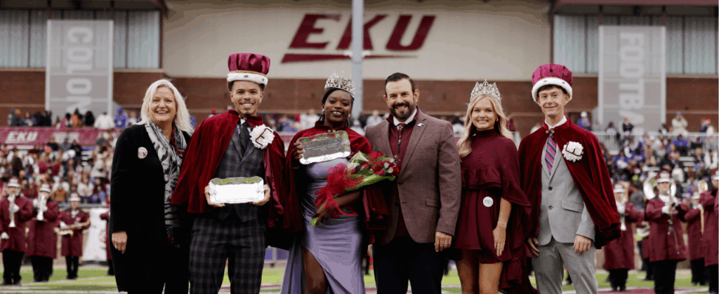 president mcfaddin stands with the homecoming king and queen on the football field at eku