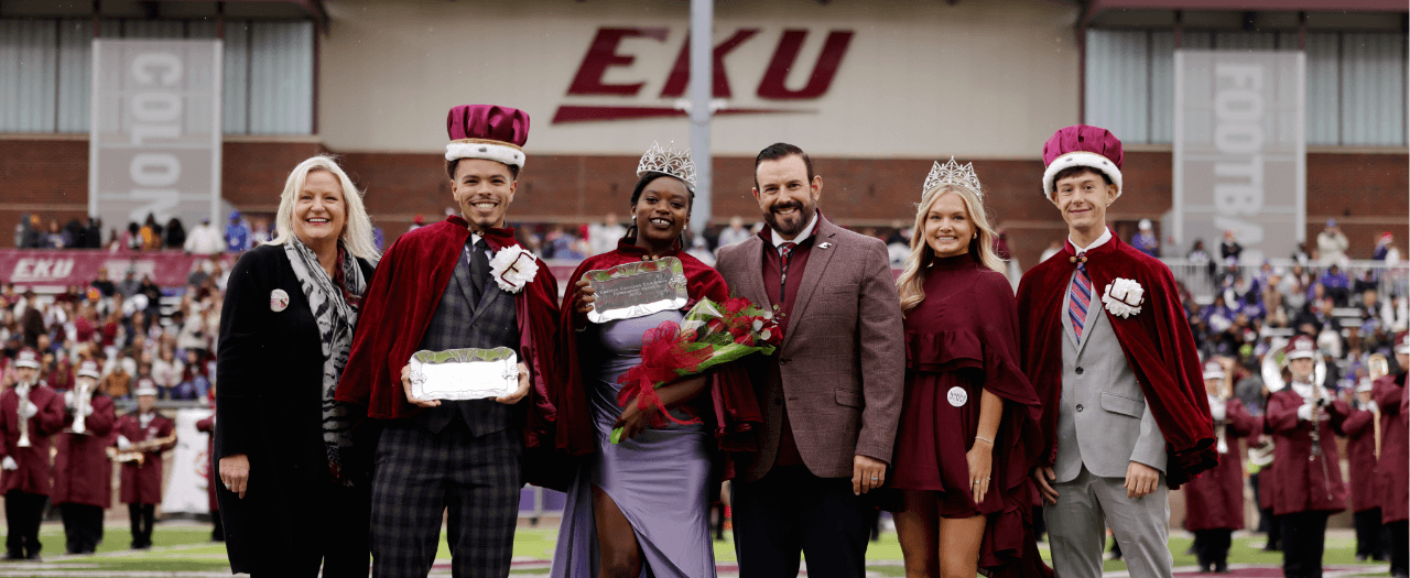 president mcfaddin stands with the homecoming king and queen on the football field at eku