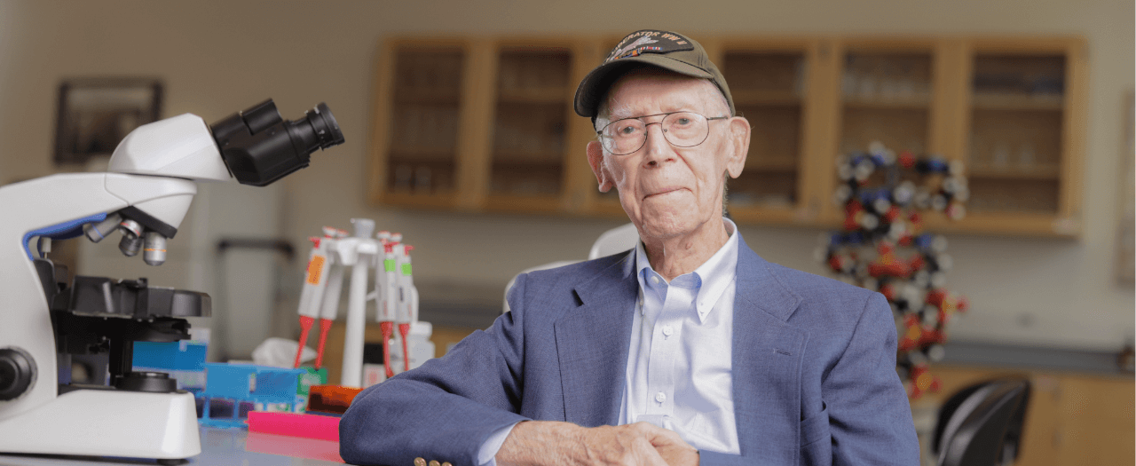 photo of dr sanford jones sitting in a lab next to a microscope