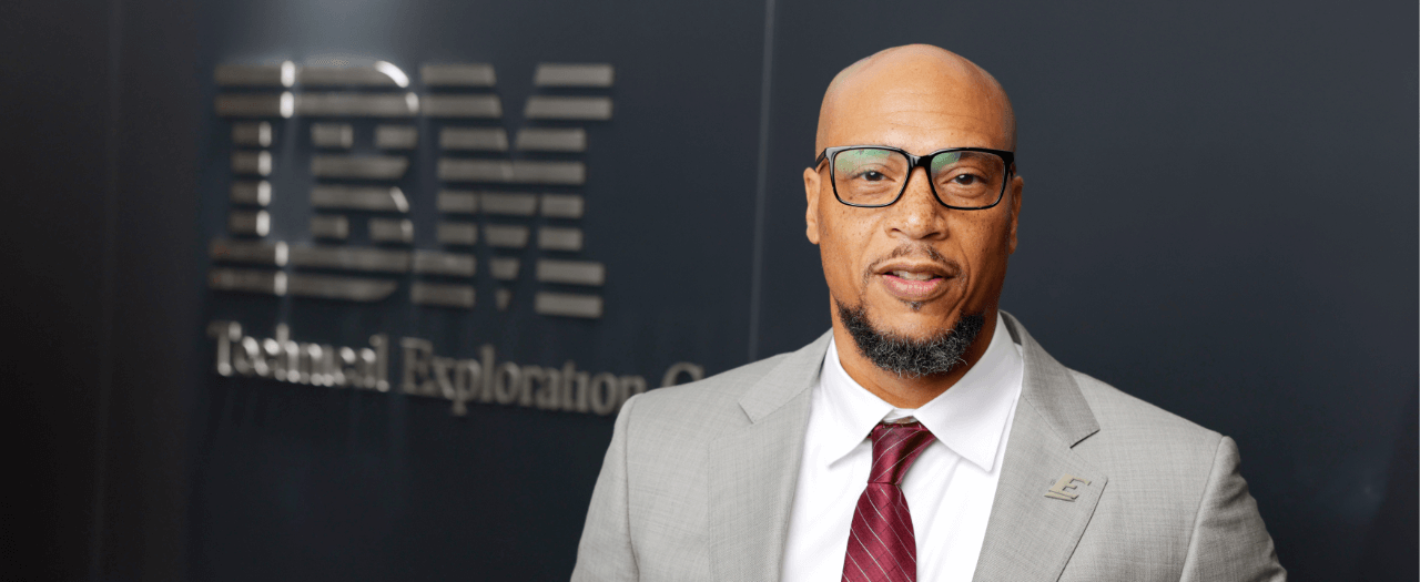 Ervin Daniels in the foreground with the IBM logo on the wall in the background