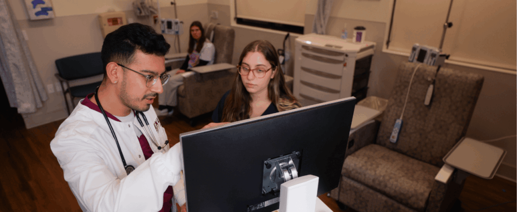 eku nursing students look at a monitor in a room with medical equipment