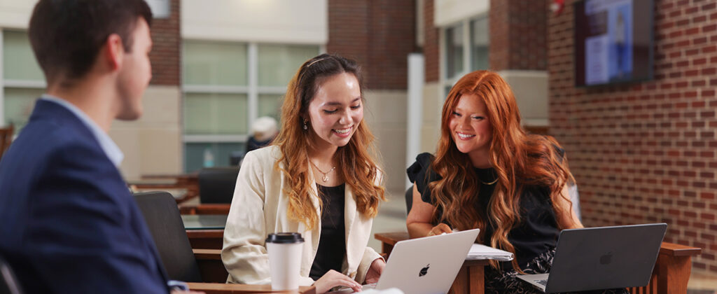 Two professionally dressed female business students work together from their computers in EKU's Business & Technology Center.