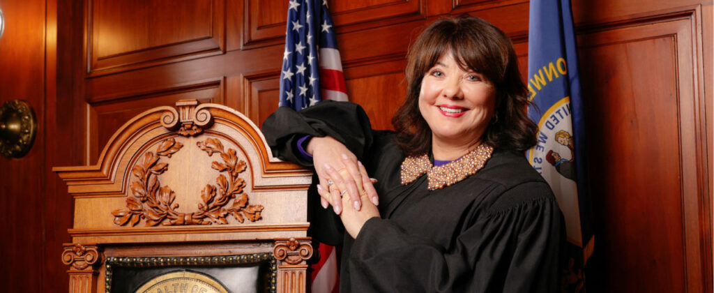 Chief Justice Debra Hembree Lambert poses in her robe in a courtroom for a professional photo.