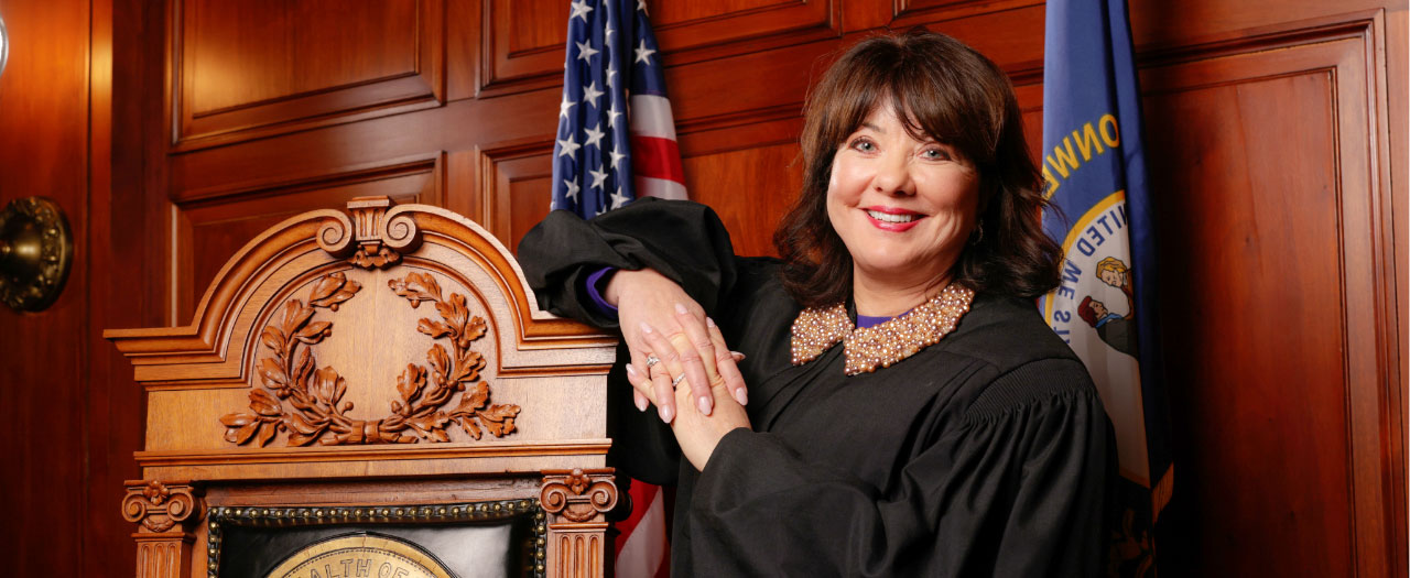 Chief Justice Debra Hembree Lambert poses in her robe in a courtroom for a professional photo.