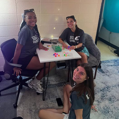 Three female students gather around a table to play a game