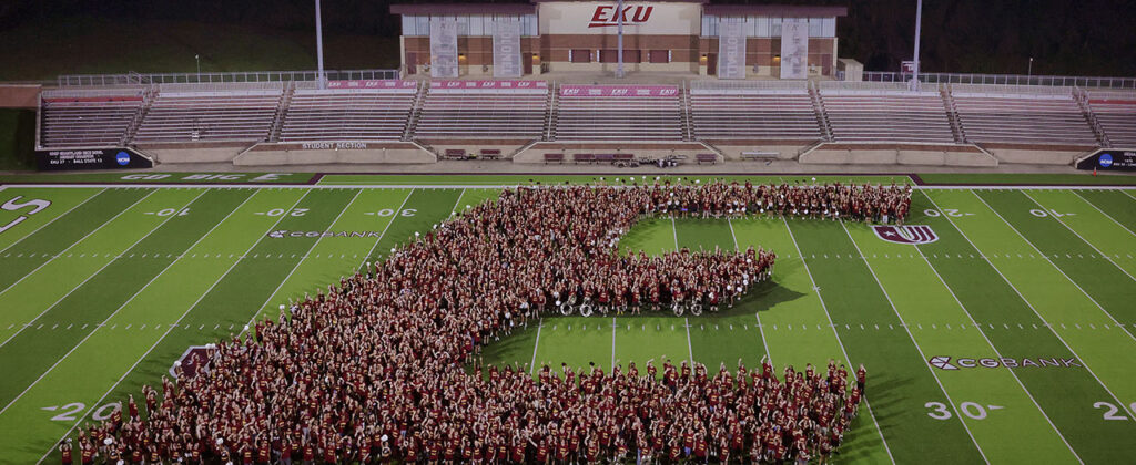 Banner image of students on a sports field creating the EKU E logo